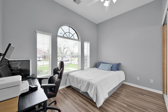 bedroom with high vaulted ceiling, an office area, wood finished floors, baseboards, and a ceiling fan