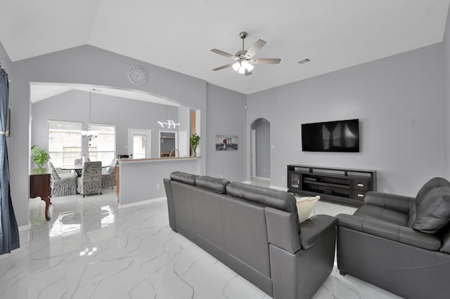living area featuring arched walkways, vaulted ceiling, a ceiling fan, light marble finish floors, and a chandelier