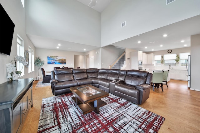 22110 Sam Raburn Dr, Tomball, TX 77375 - living area featuring light wood-style flooring, stairway, a towering ceiling, and recessed lighting