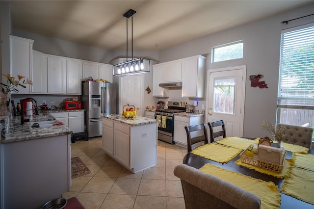 32102 Annice Ln, Pinehurst, TX 77362 - kitchen featuring stainless steel appliances, under cabinet range hood, light tile patterned flooring, a sink, and white cabinets
