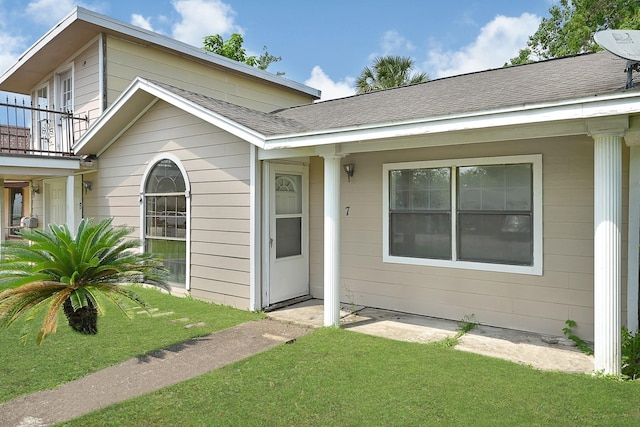 view of front of home with a balcony, a front lawn, and roof with shingles