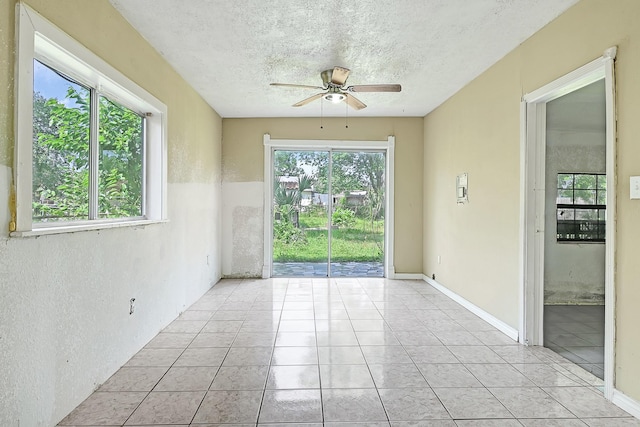 unfurnished room with ceiling fan, light tile patterned floors, and a textured ceiling