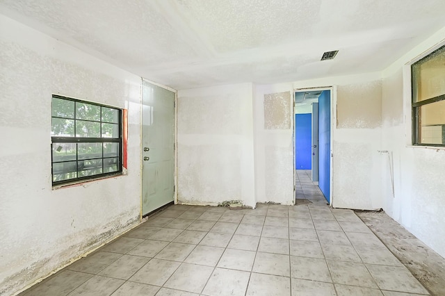 unfurnished room with a textured ceiling and light tile patterned floors