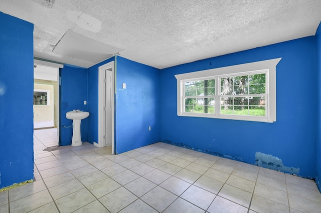 unfurnished room with tile patterned flooring, a sink, and a textured ceiling