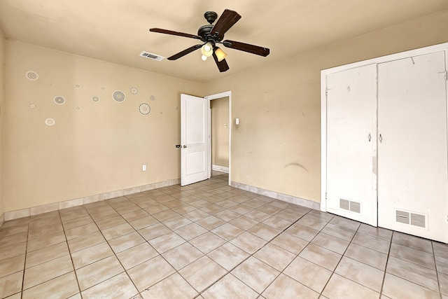 spare room featuring ceiling fan, light tile patterned floors, and baseboards