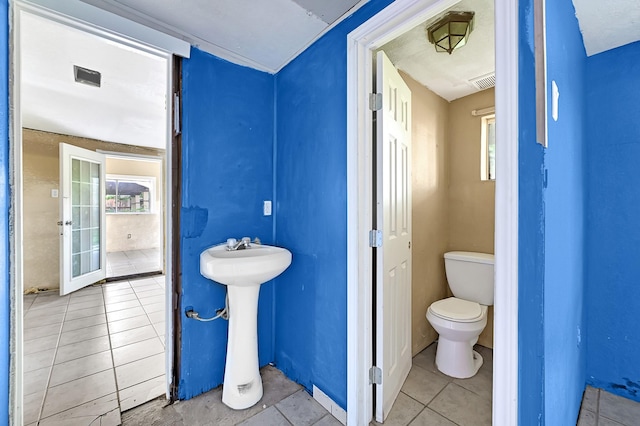bathroom featuring toilet, tile patterned flooring, a sink, and healthy amount of natural light
