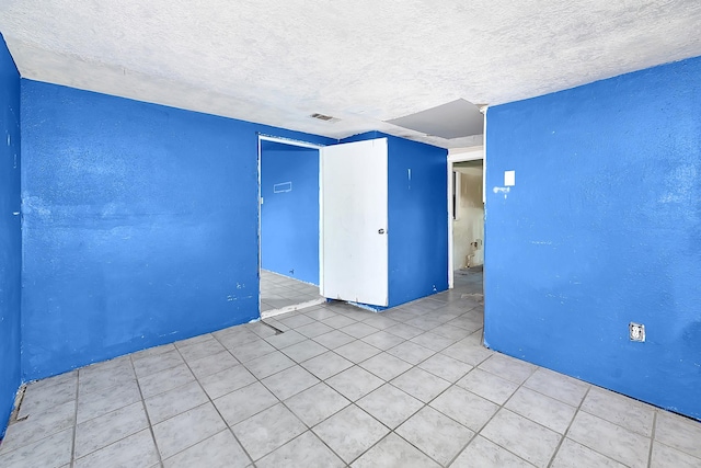 tiled spare room featuring a textured ceiling