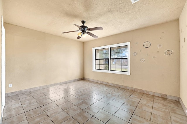 spare room with a ceiling fan, light tile patterned flooring, baseboards, and a textured ceiling