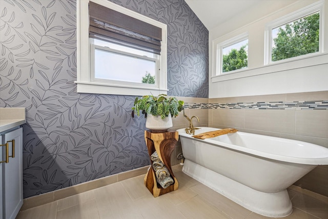 bathroom featuring wallpapered walls, a soaking tub, and vanity