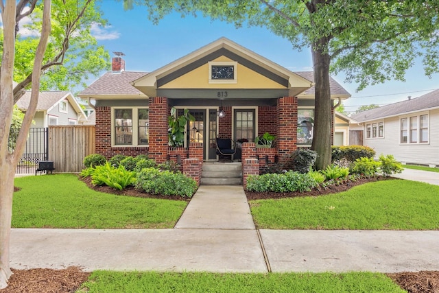 bungalow-style house featuring brick siding, a chimney, and covered porch