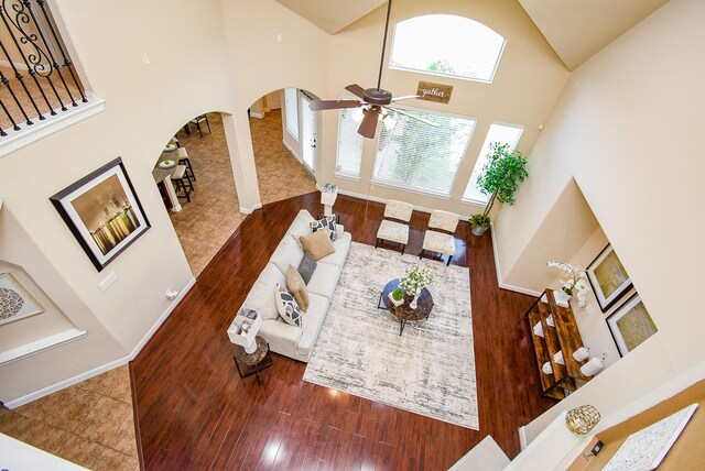 7003 Paxton Ct, Sugar Land, TX 77479 - living room with high vaulted ceiling, wood finished floors, a ceiling fan, arched walkways, and baseboards