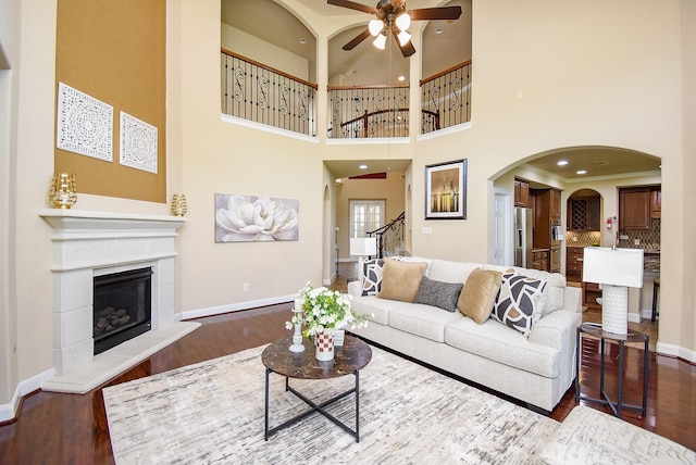 7003 Paxton Ct, Sugar Land, TX 77479 - living room featuring ceiling fan, wood finished floors, a glass covered fireplace, baseboards, and a high ceiling
