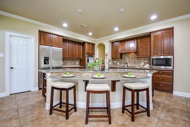 7003 Paxton Ct, Sugar Land, TX 77479 - kitchen with appliances with stainless steel finishes, a spacious island, backsplash, a breakfast bar, and crown molding
