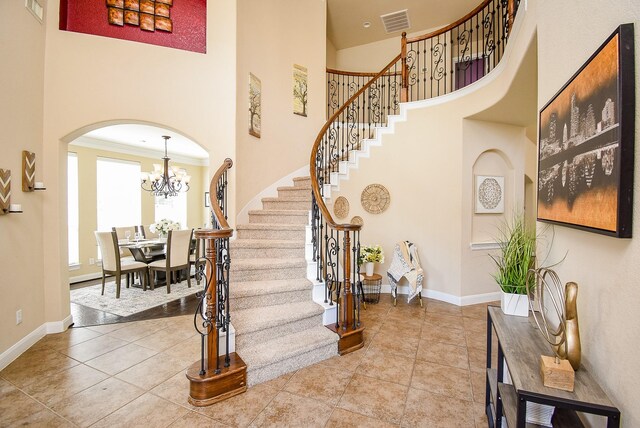 7003 Paxton Ct, Sugar Land, TX 77479 - tiled entrance foyer with arched walkways, stairs, a high ceiling, baseboards, and a chandelier