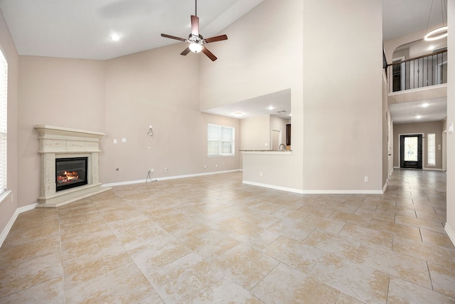 27106 Cottage Stream Ln, Fulshear, TX 77441 - unfurnished living room with high vaulted ceiling, a ceiling fan, a glass covered fireplace, and baseboards