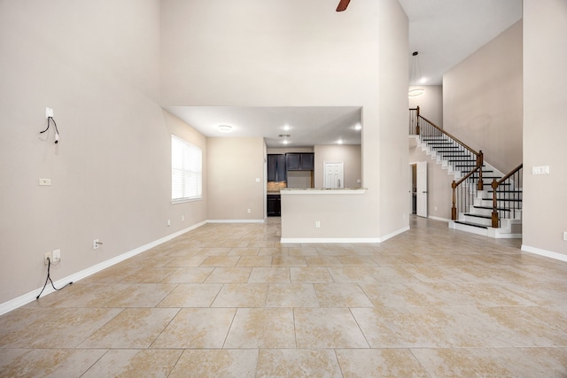 27106 Cottage Stream Ln, Fulshear, TX 77441 - unfurnished living room with a high ceiling, stairway, baseboards, a ceiling fan, and light tile patterned floors