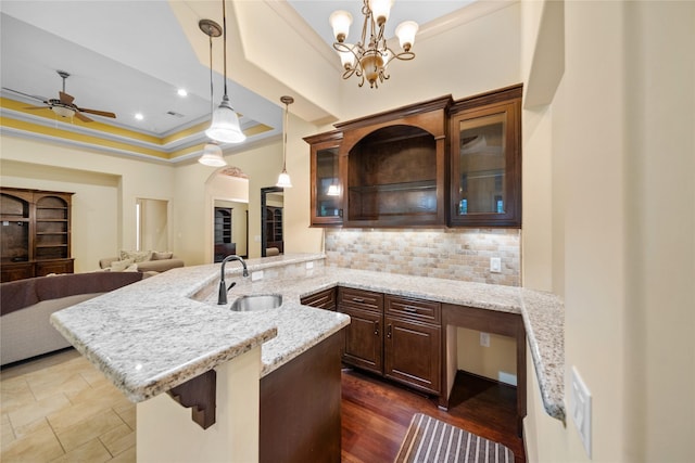 kitchen featuring a sink, decorative backsplash, crown molding, dark brown cabinetry, and a ceiling fan