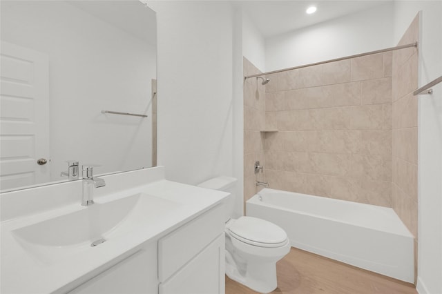 bathroom featuring wood finished floors, toilet, vanity, and washtub / shower combination