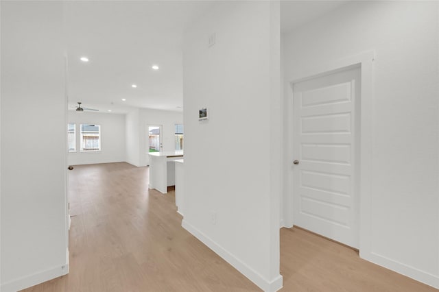 corridor featuring light wood-style flooring, recessed lighting, and baseboards