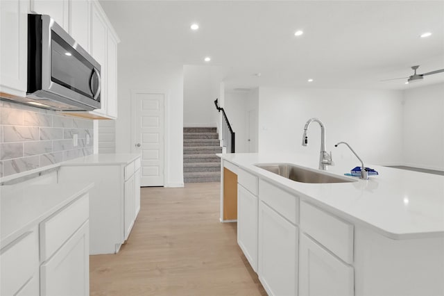 3907 Knighton Ct, Fulshear, TX 77441 - kitchen featuring stainless steel microwave, a sink, recessed lighting, light wood-type flooring, and a center island with sink