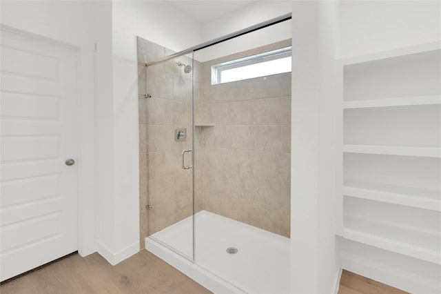 full bathroom featuring a shower stall and wood finished floors