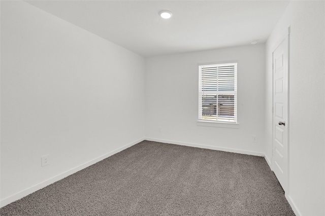 empty room with dark colored carpet and baseboards