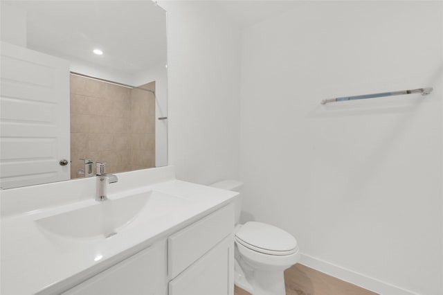 bathroom featuring vanity, toilet, baseboards, recessed lighting, and a shower