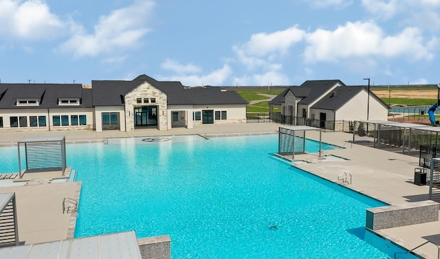 community pool with a patio area and fence