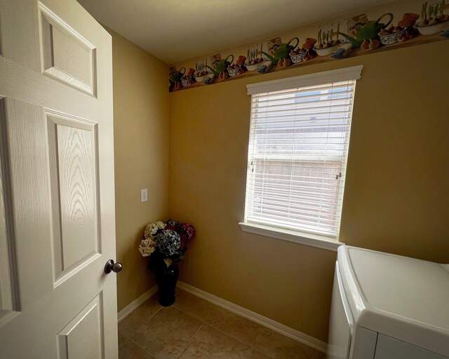 laundry area featuring washer / clothes dryer, healthy amount of natural light, light tile patterned floors, and baseboards