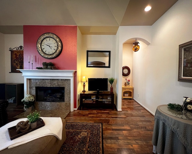 living area featuring arched walkways, wood finished floors, recessed lighting, a high end fireplace, and baseboards