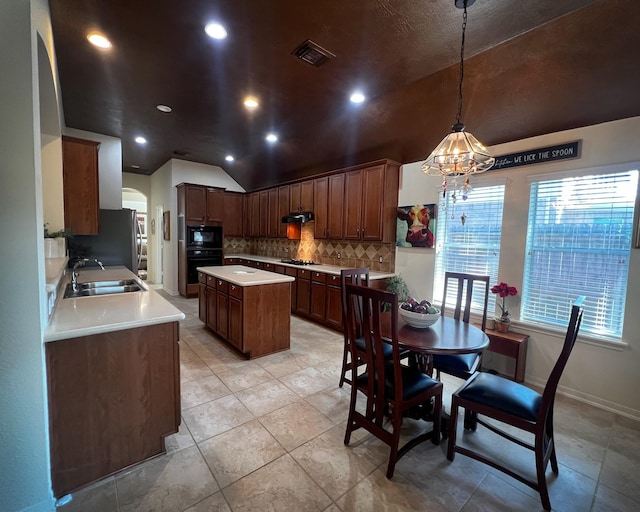 kitchen featuring vaulted ceiling, black appliances, a sink, tasteful backsplash, and a center island