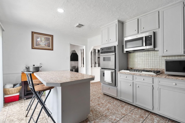4914 Airport Blvd, Houston, TX 77048 - kitchen featuring appliances with stainless steel finishes, light countertops, backsplash, a textured ceiling, and light tile patterned floors