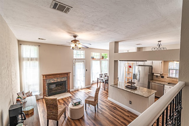 20423 Lone Star Oak St, Cypress, TX 77433 - living room featuring wood finished floors, a ceiling fan, a fireplace, a textured ceiling, and a textured wall