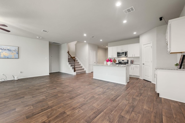 4438 Andorno Dr, Katy, TX 77449 - kitchen featuring appliances with stainless steel finishes, open floor plan, recessed lighting, white cabinets, and dark wood-type flooring