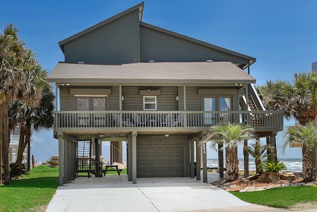 4242 Pelican Ln, Galveston, TX 77554 - beach home with stairway, covered porch, a garage, concrete driveway, and a shingled roof