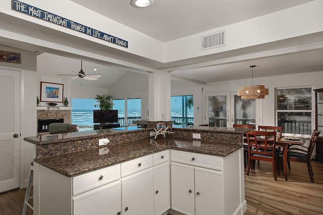 4242 Pelican Ln, Galveston, TX 77554 - kitchen featuring open floor plan, wood finished floors, white cabinets, dark stone counters, and lofted ceiling