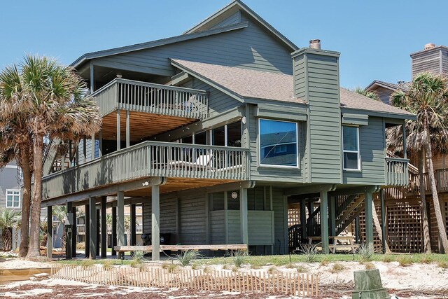 4242 Pelican Ln, Galveston, TX 77554 - rear view of property featuring a shingled roof, a wooden deck, a chimney, stairway, and a balcony