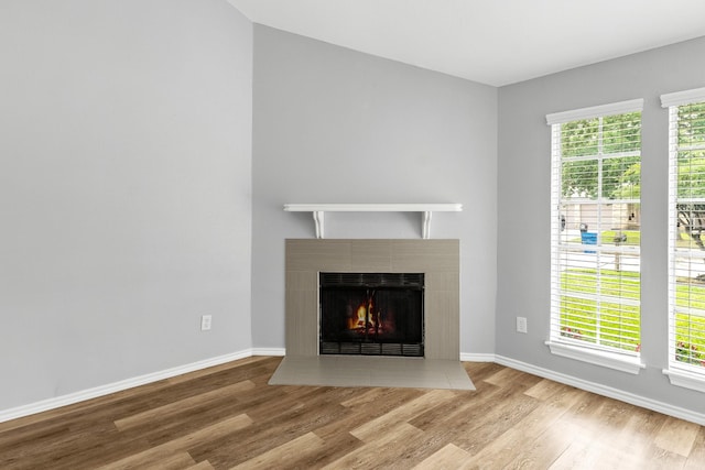 unfurnished living room featuring wood finished floors, baseboards, and a fireplace with flush hearth