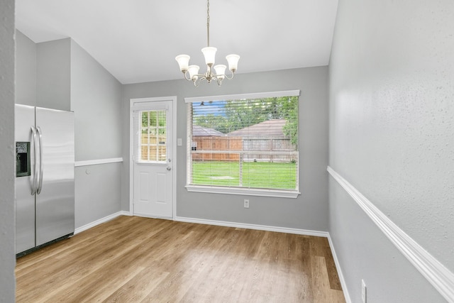 unfurnished dining area with wood finished floors, a chandelier, and healthy amount of natural light