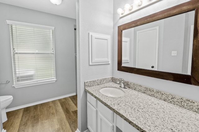 bathroom featuring wood finished floors, vanity, baseboards, and toilet
