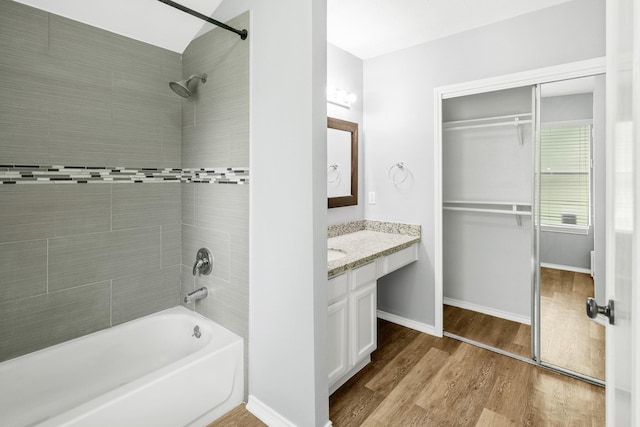 bathroom with wood finished floors, vanity,  shower combination, and baseboards
