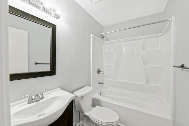 full bath featuring toilet, vanity, a textured wall, and  shower combination