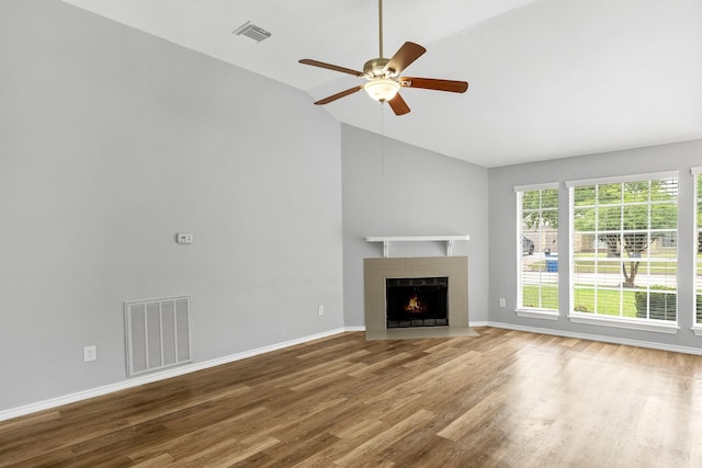 unfurnished living room featuring lofted ceiling, wood finished floors, ceiling fan, a fireplace with flush hearth, and baseboards