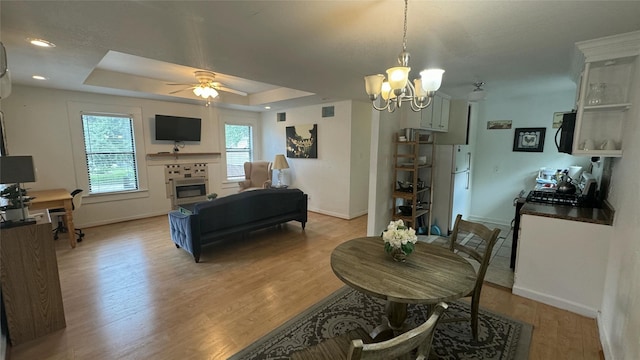 dining space with baseboards, a chandelier, light wood-style floors, and a ceiling fan
