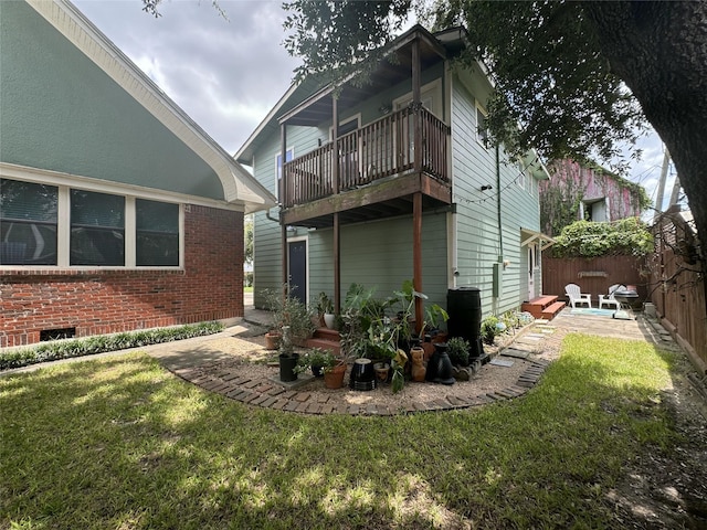 rear view of house featuring a balcony, brick siding, and a patio area