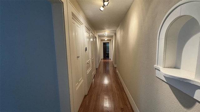 hallway with dark wood-type flooring and baseboards