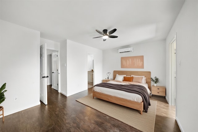 bedroom with a wall mounted air conditioner, wood finished floors, baseboards, ceiling fan, and connected bathroom