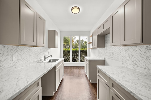 kitchen with a sink, gray cabinets, decorative backsplash, and dark wood finished floors
