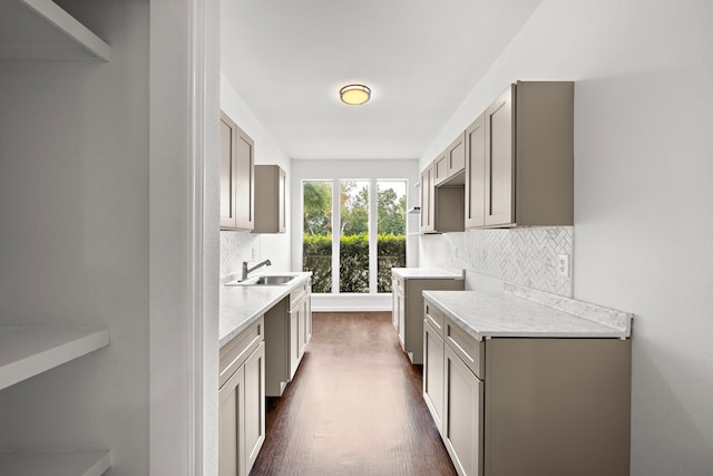 kitchen with a sink, decorative backsplash, dark wood-style flooring, and light countertops