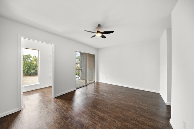 empty room with dark wood-style floors, a ceiling fan, and baseboards